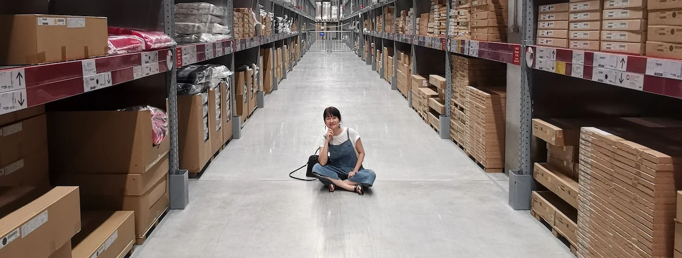 Smiling woman sitting in the middle of a warehouse