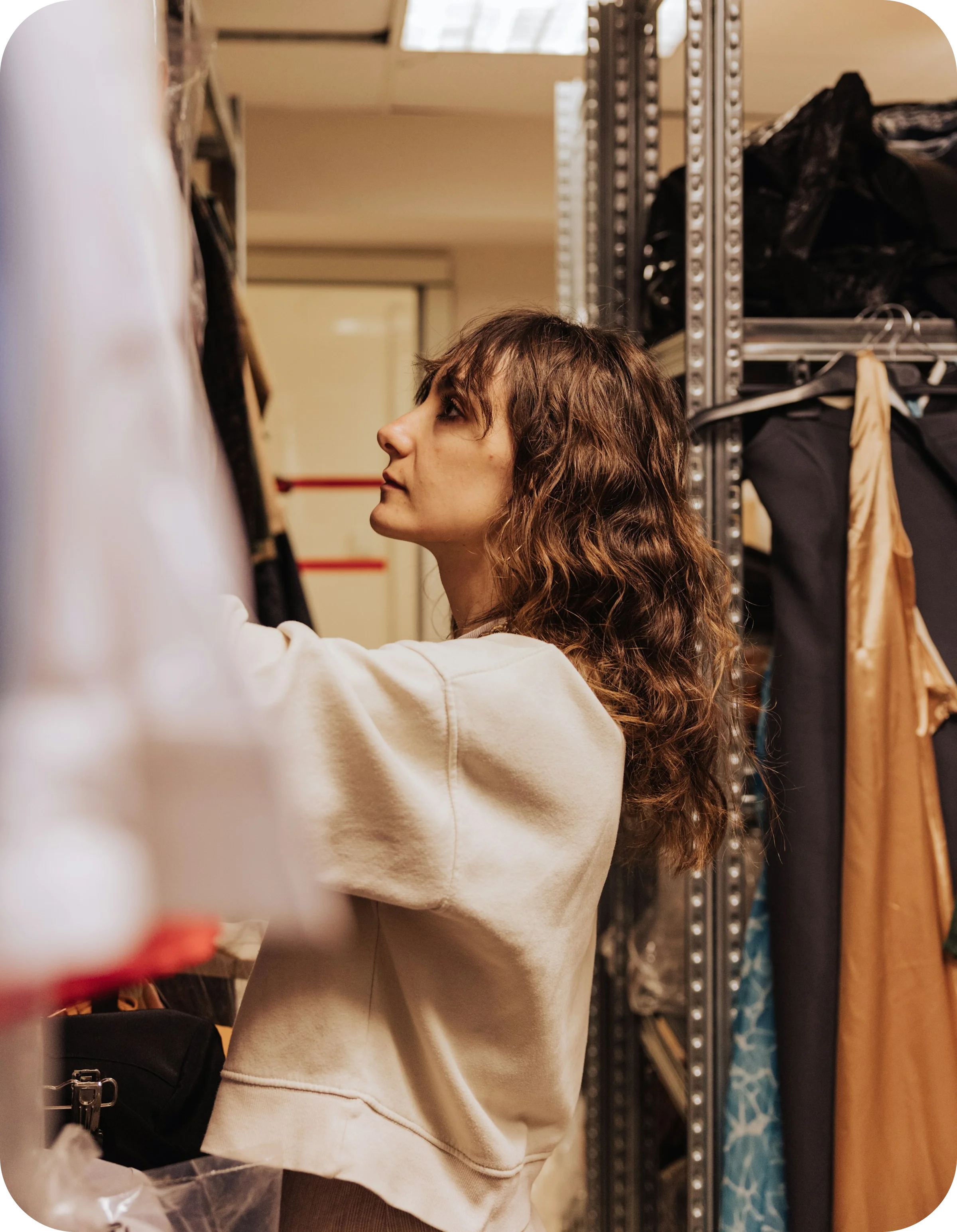 Woman with brown hair scrolling through clothing rack