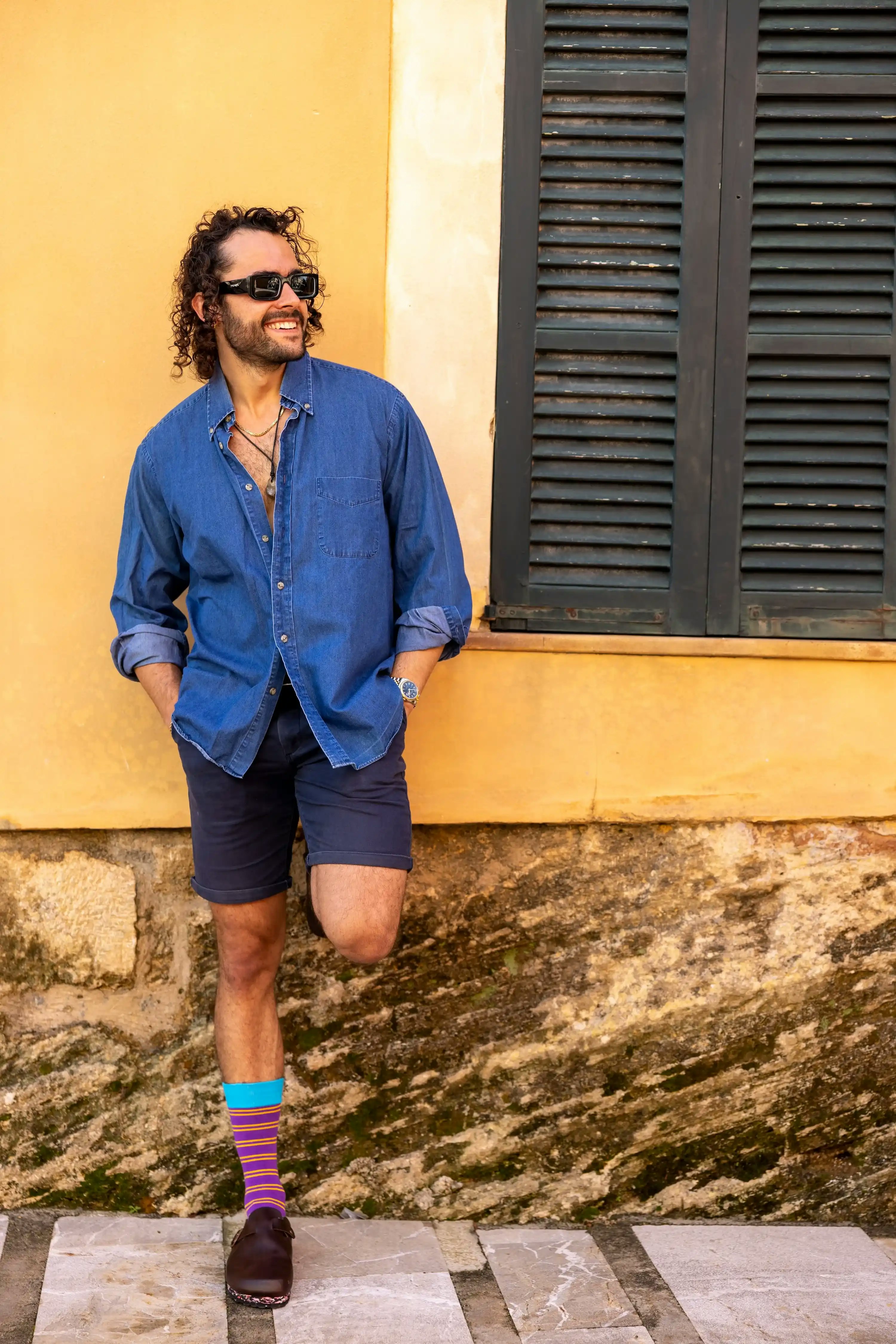 Man with colorful striped socks from Swole Panda, standing in front of a yellow wall