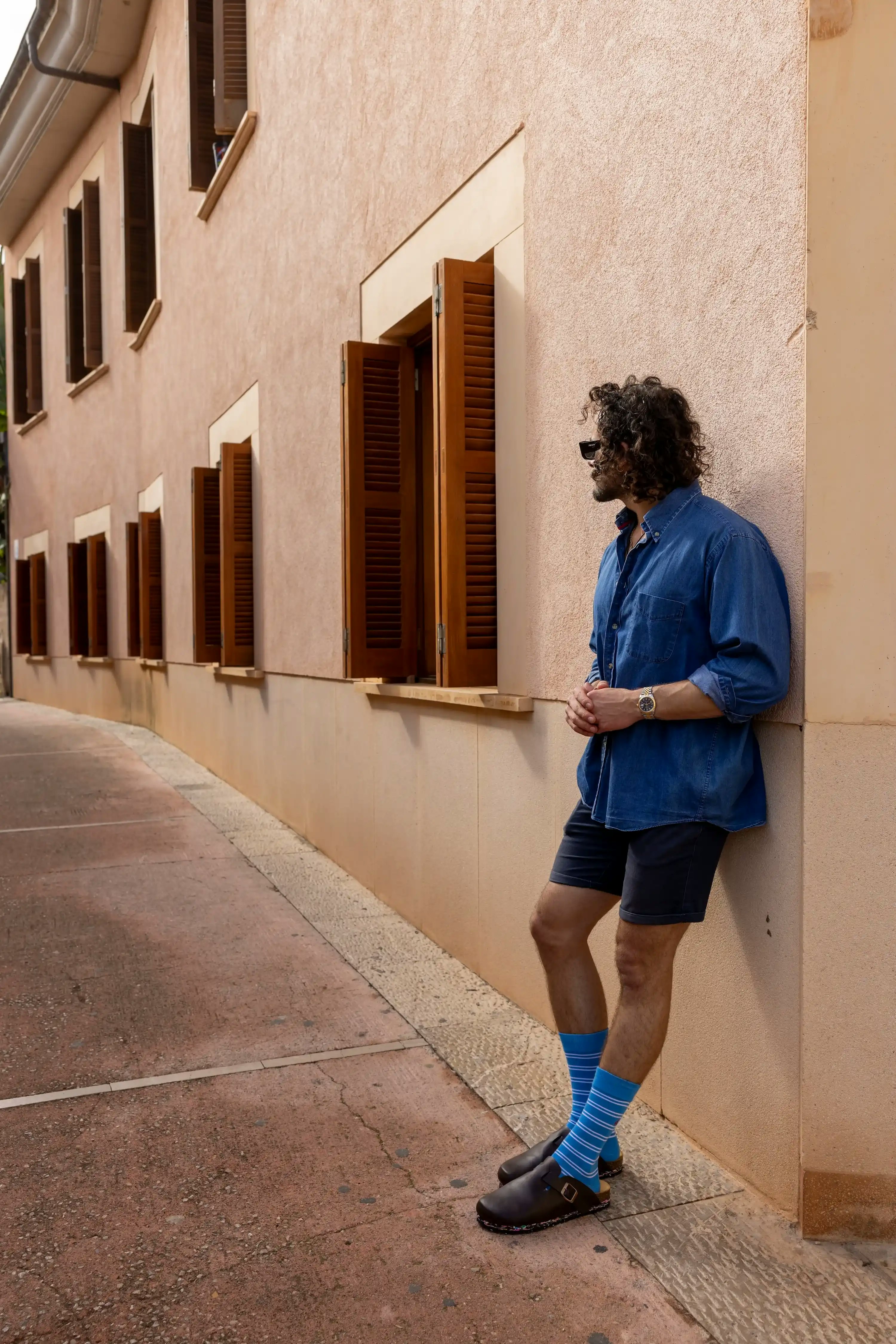 man with blue striped Swole Panda socks leaning against a wall casually