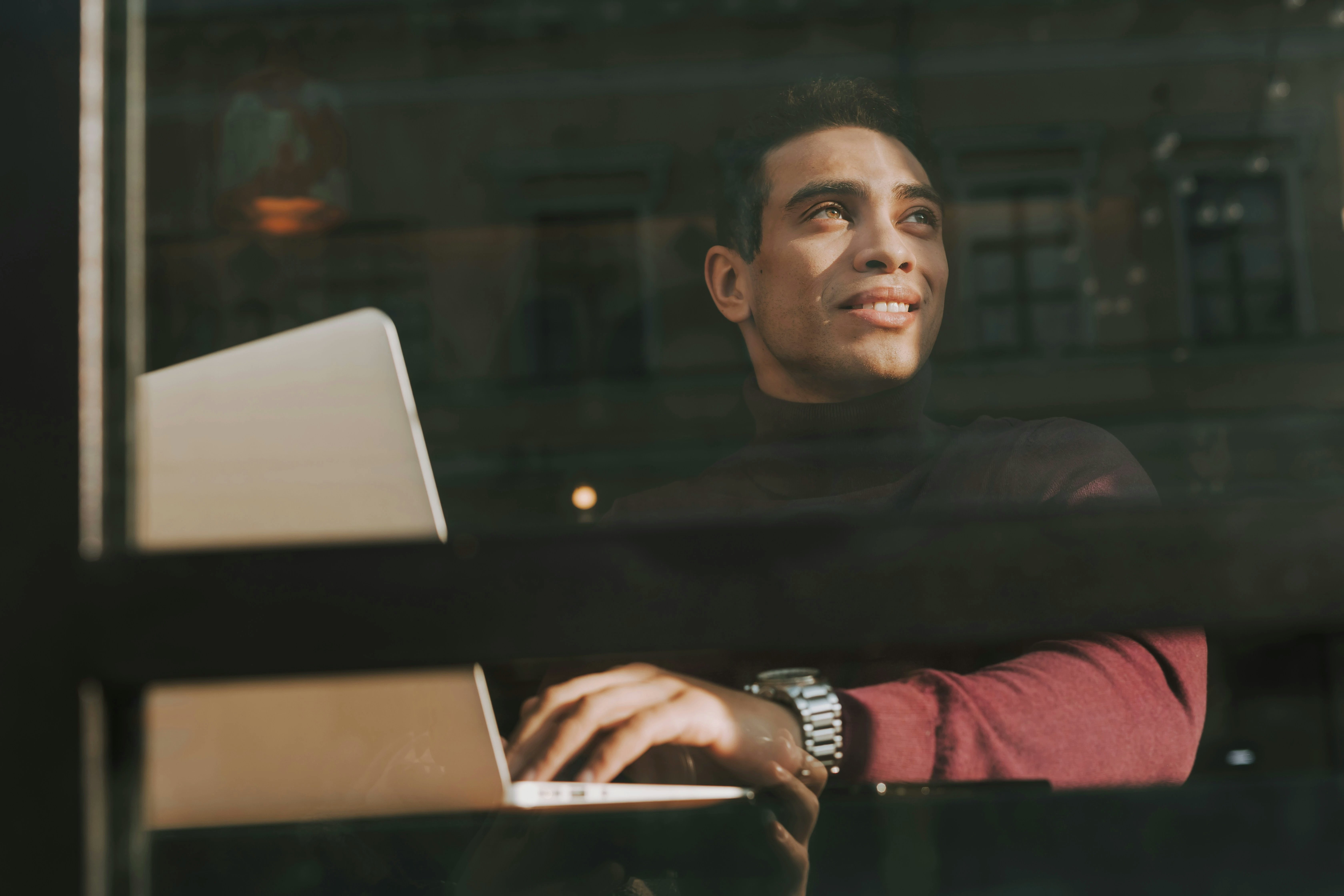 Man working on laptop looking out through window
