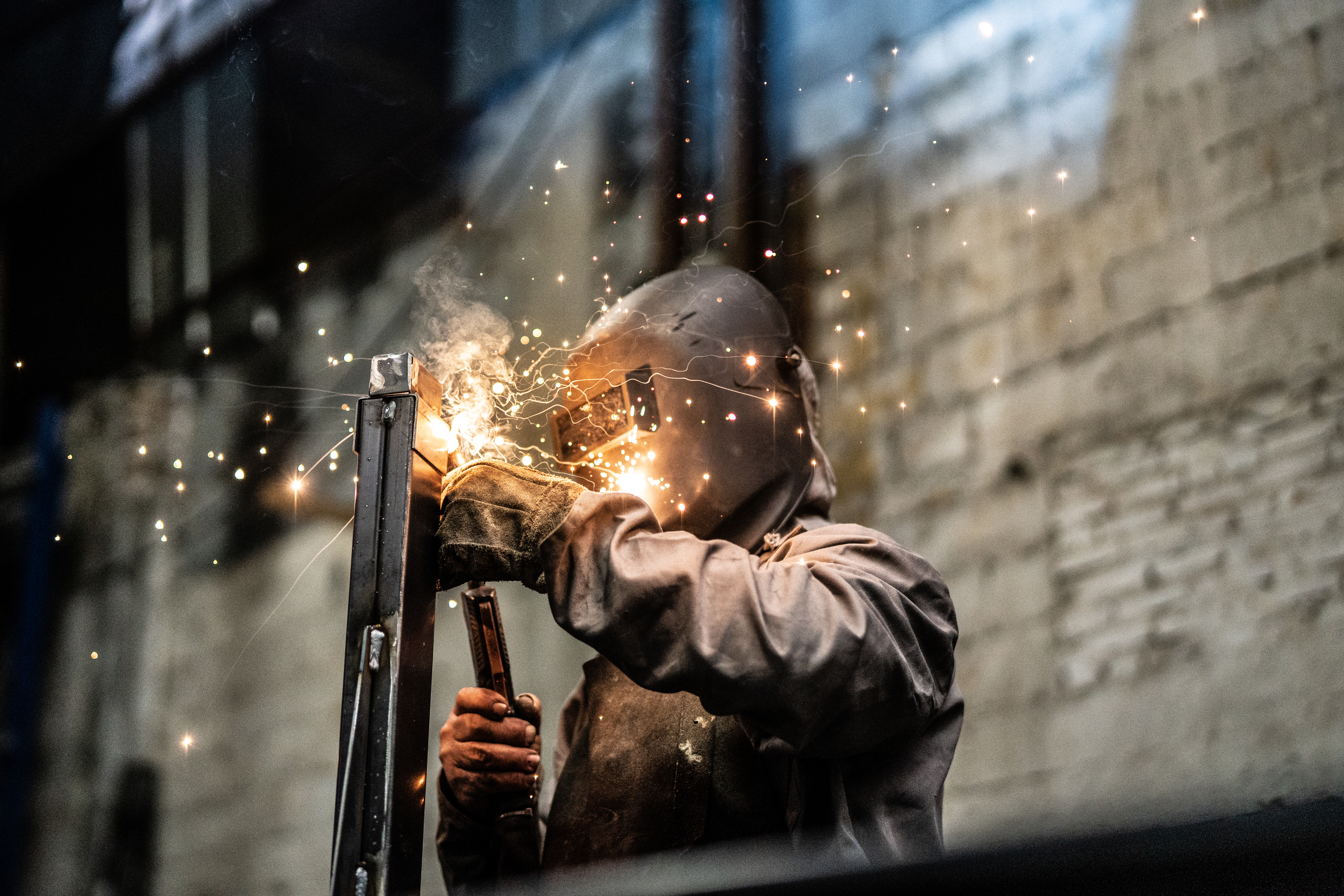 A man wearing protective gear welding materials together