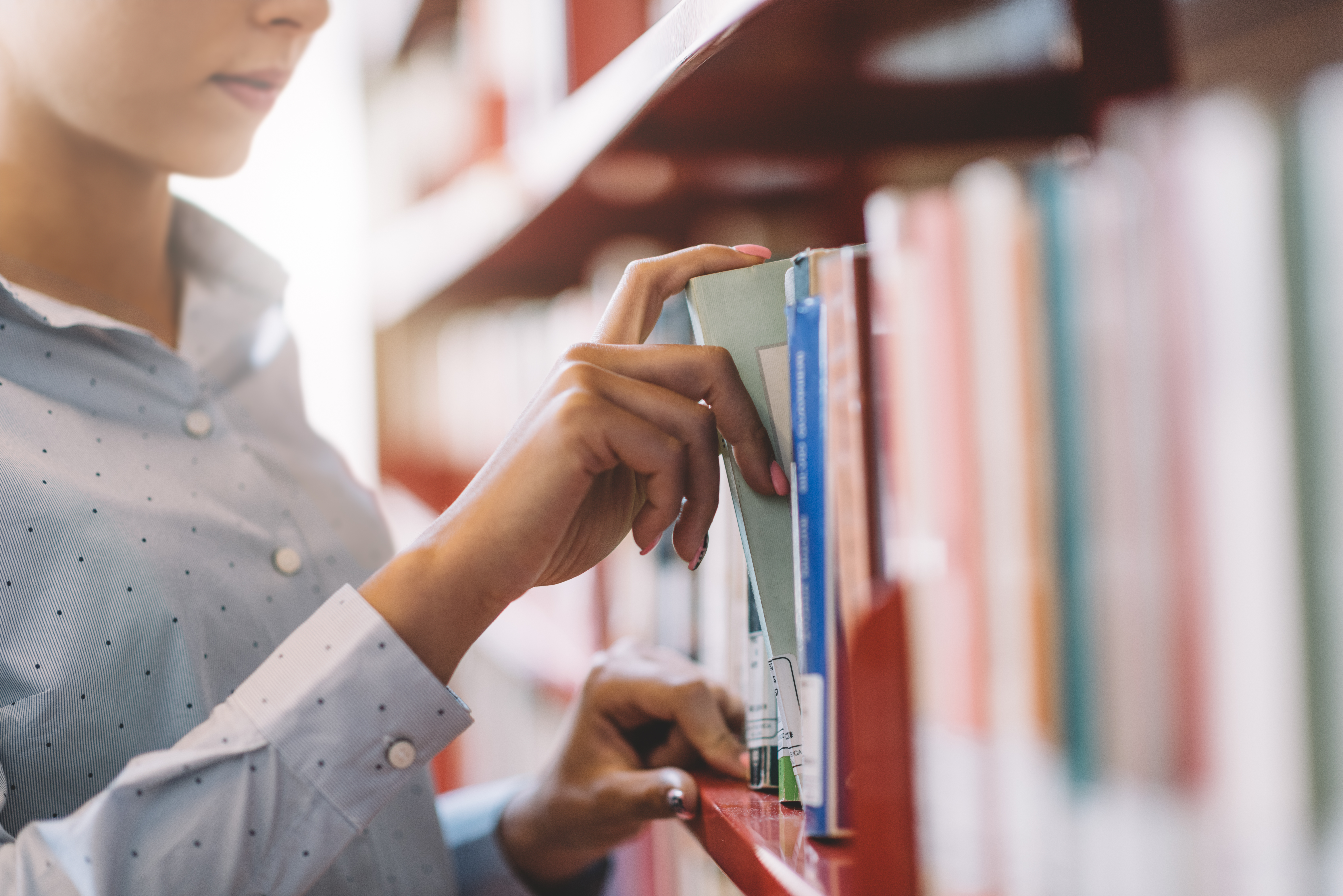 Woman pulling a book out from a large bookshelf