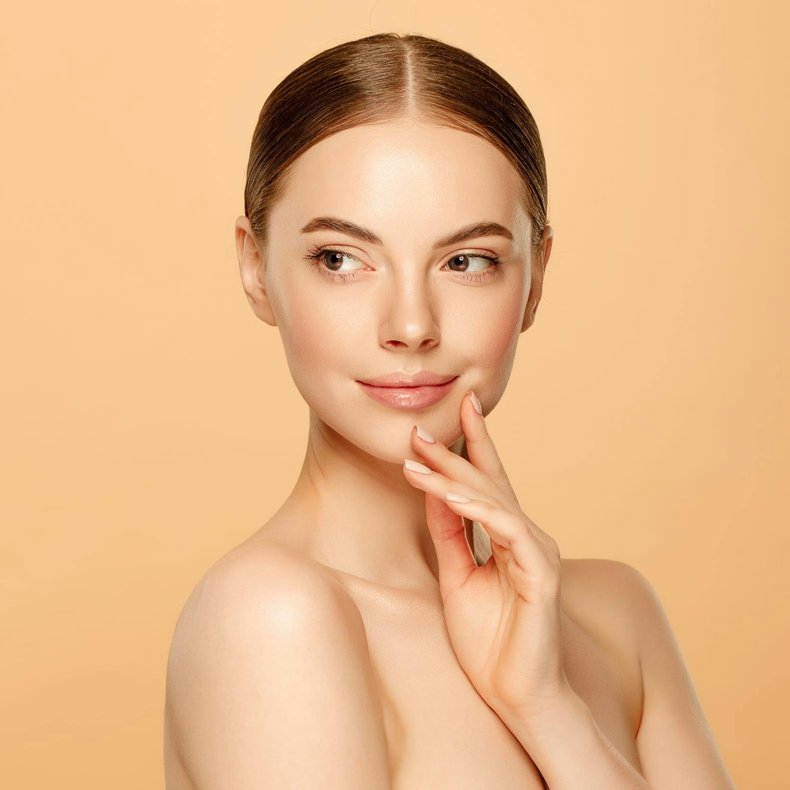 Woman with her hair slicked back in a ponytail, touching her lower face