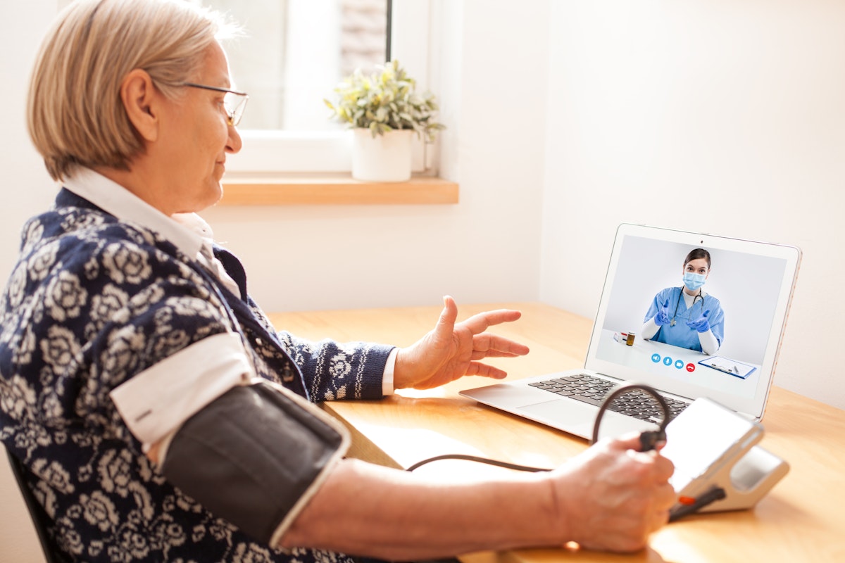 Senior woman having a teleconsultation and checking her blood pressure