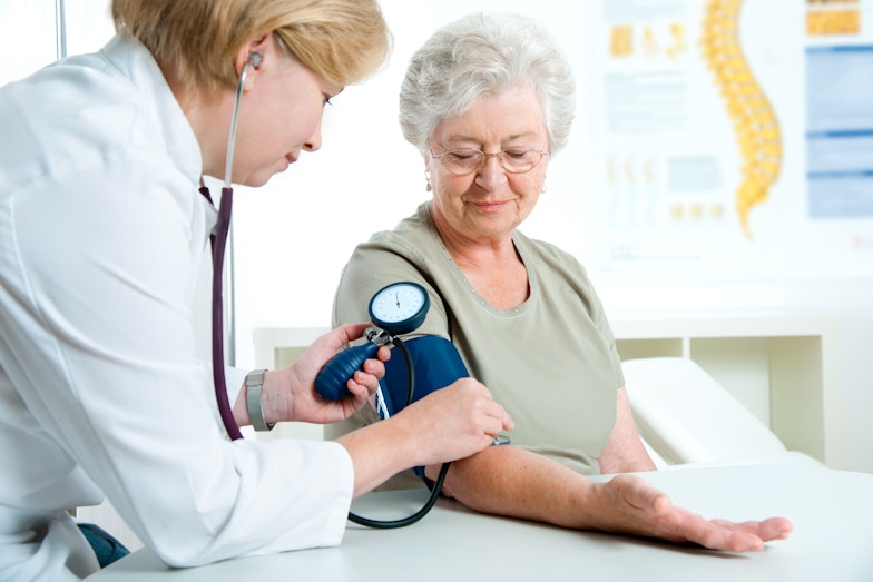 Médico verifica a pressão arterial de uma mulher idosa