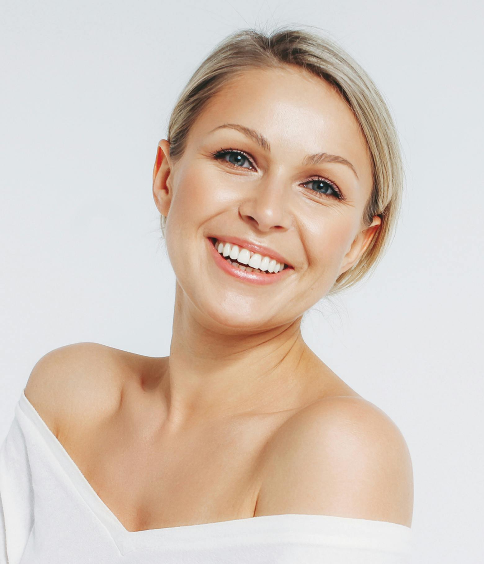Woman smiling wearing a white top that hangs off the shoulders