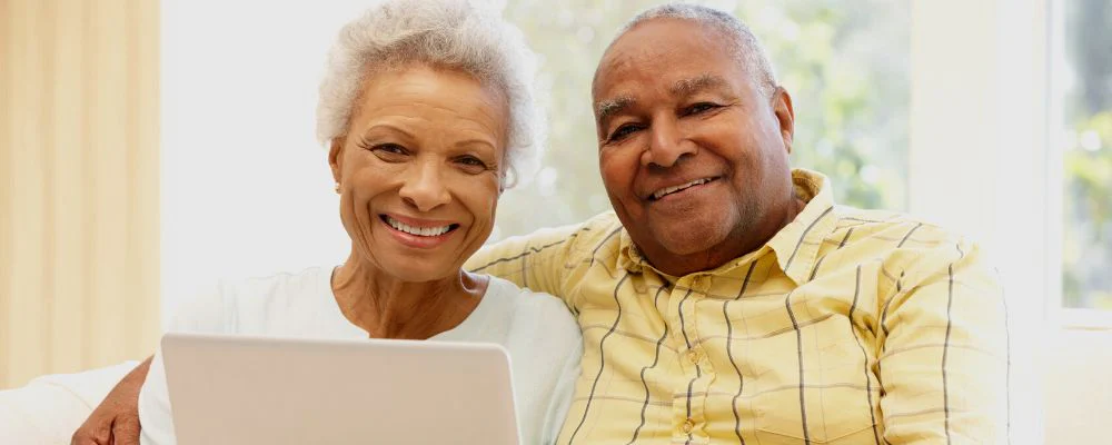 Older man and woman smiling in front of computer