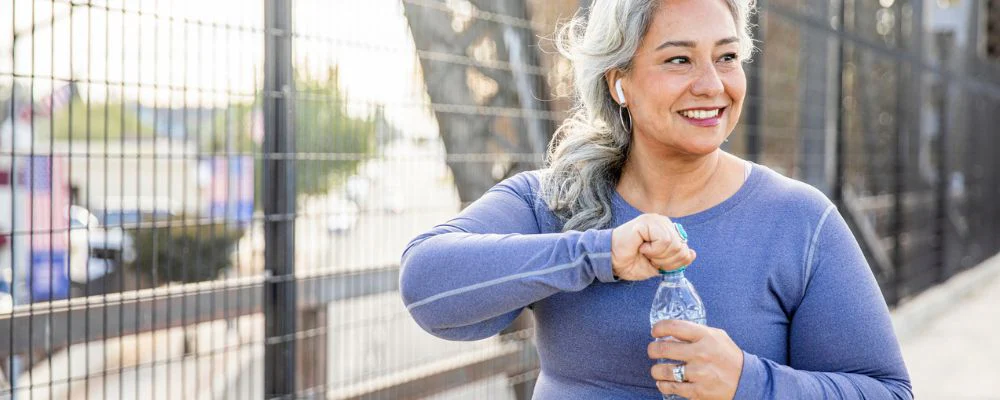 Older woman hydrating with water on walk outside
