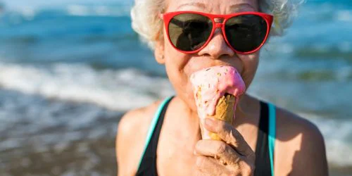 older woman eating ice cream at the beach in the summer