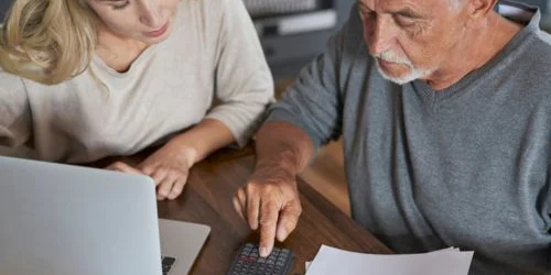 Two adults with computer, bill, and calculator