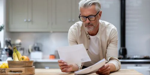 older man looking at two pieces of paper