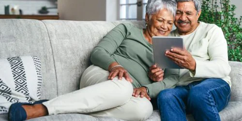 older couple sitting on couch doing research on tablet