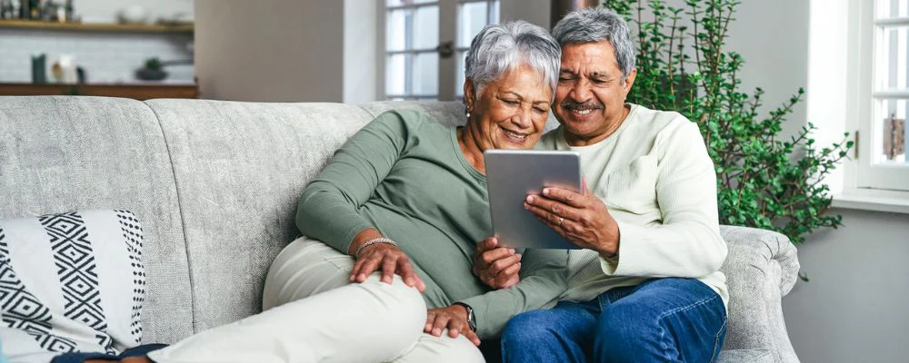 older couple sitting on couch doing research on tablet