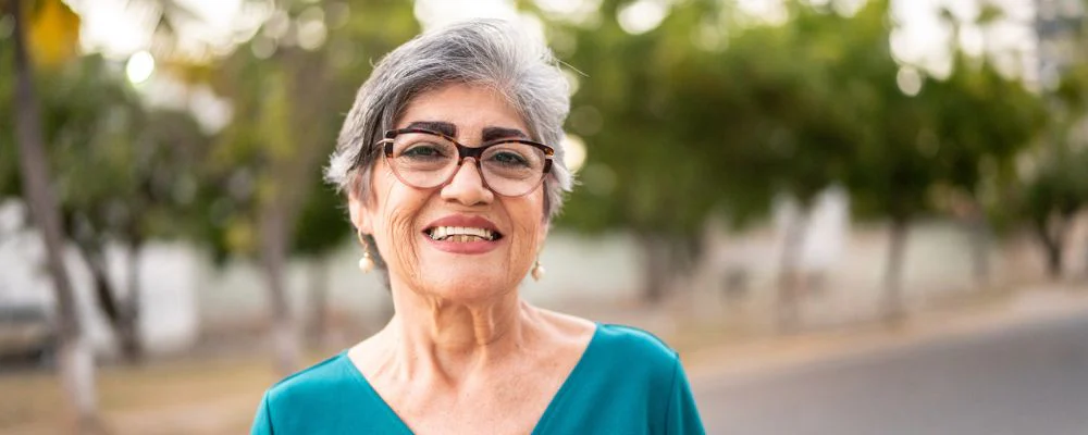 older adult woman standing outside smiling at camera