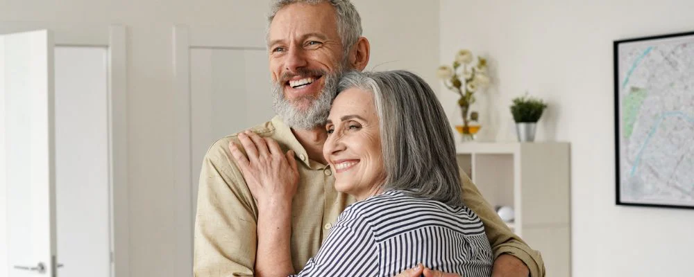 Two older adults embracing in living room