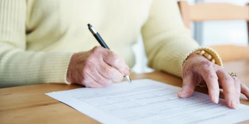 older woman filling out form on desk