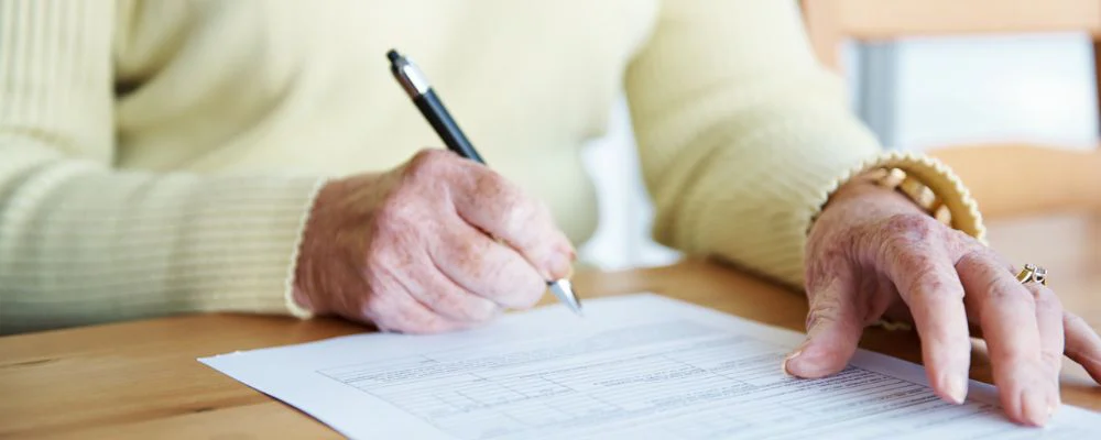 Older woman filling out form on desk