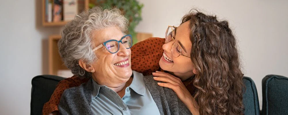 Older woman smiling at younger daughter after dental implant procedure