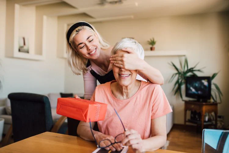 Younger family member giving wrapped gift to grandma