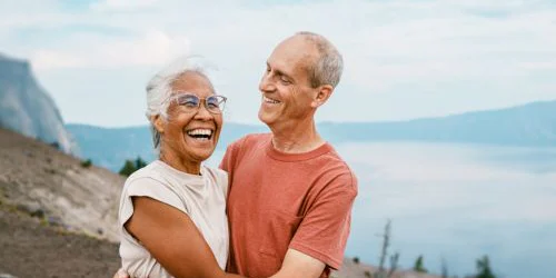 Older couple smiling and hugging with a scenic mountain background
