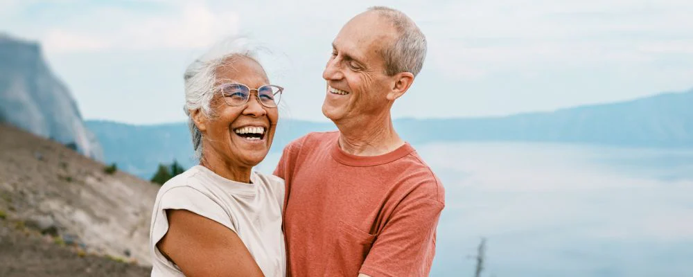 Older couple smiling and hugging with a scenic mountain background