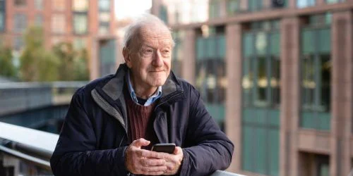 Older man in New York outside gazing with phone
