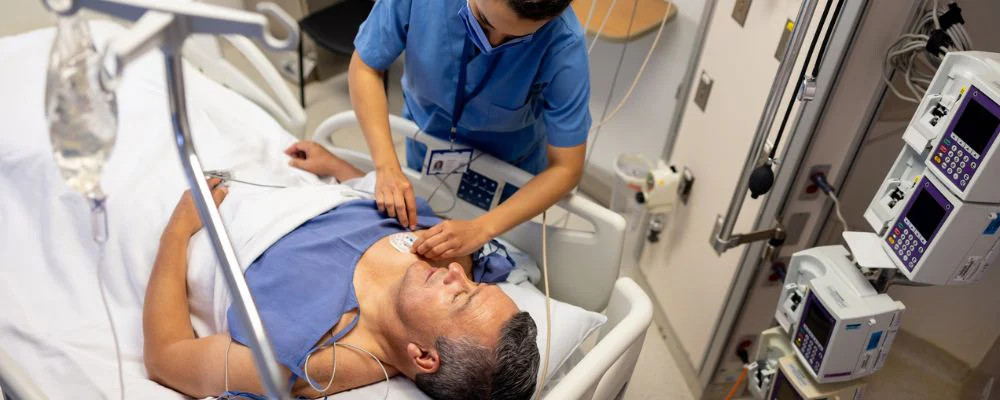 Health professional attaching electrodes to man for EKG