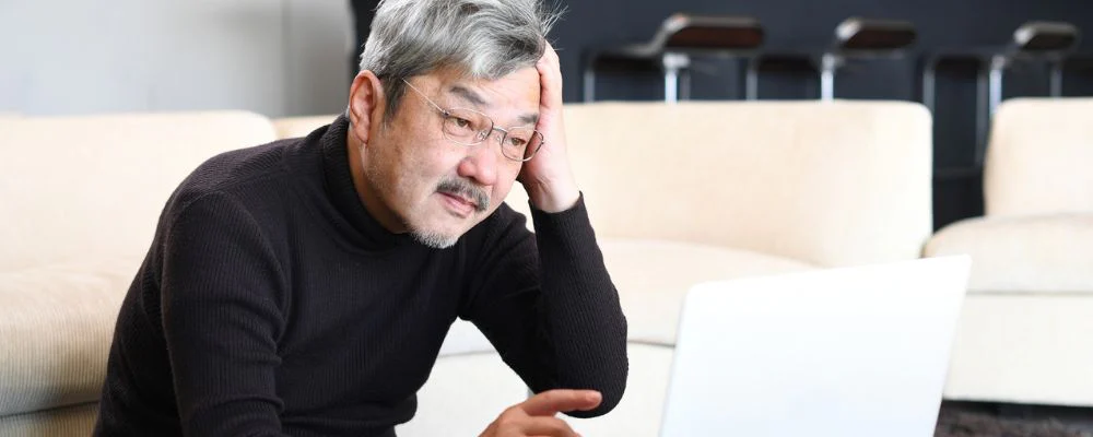 Senior man looking confused at computer screen