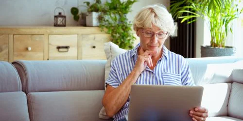 Woman thinking and looking into computer at home