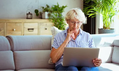 Woman thinking and looking into computer at home