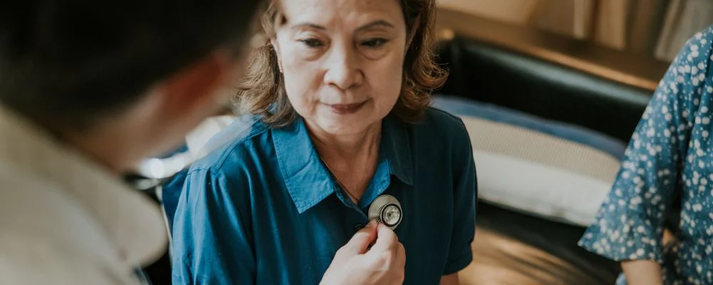 Doctor checking woman's vitals with stethoscope