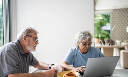 Senior couple on kitchen table with laptop