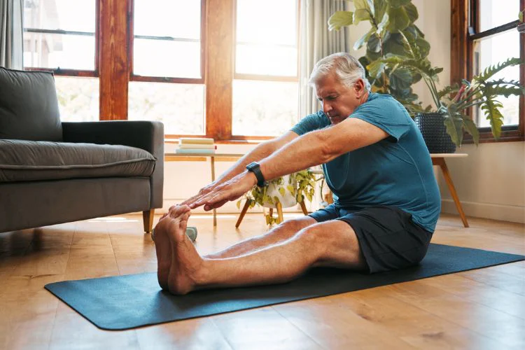 Senior man at home doing posterior leg stretch