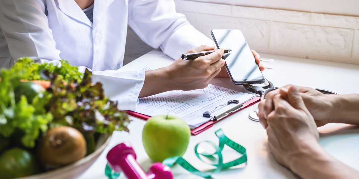 stock image of a bariatric surgeon showing results on a phone to a weight loss surgery patient in Tijuana