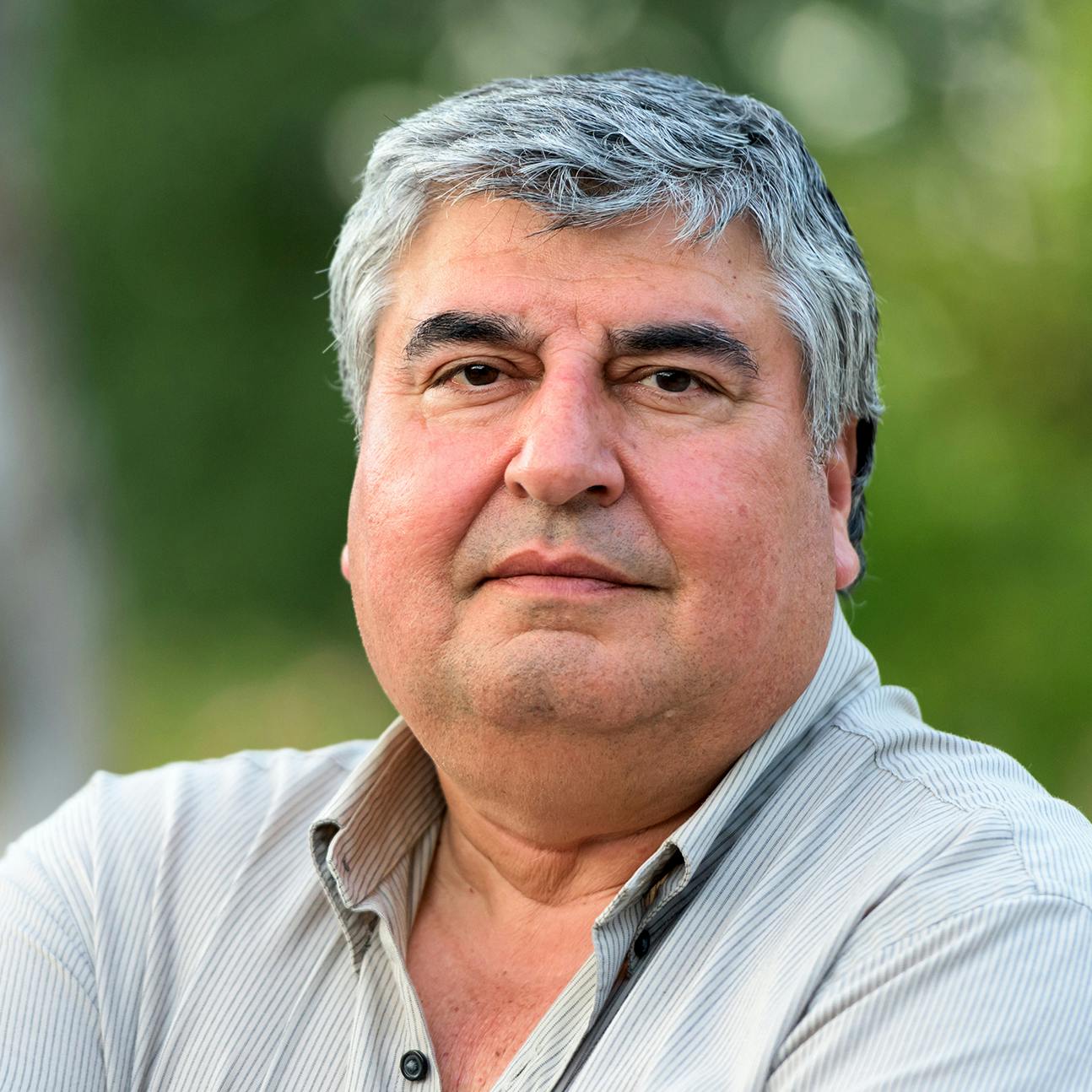 Man with grey hair wearing a grey button up shirt