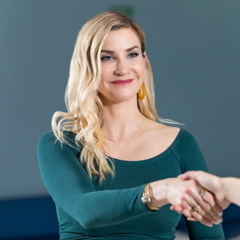 Blonde woman shaking someones hand