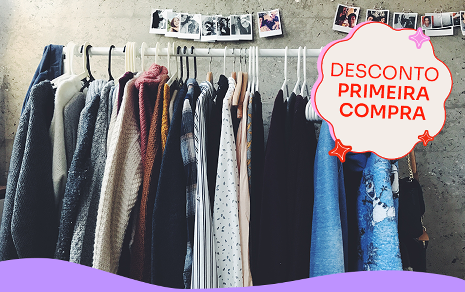 foto de uma arara de roupas, com várias peças penduradas em cabide, de frente a uma parede de cimento com fotos instantâneas penduradas em um fio. sobre a foto, um selo com o texto: desconto primeira compra.