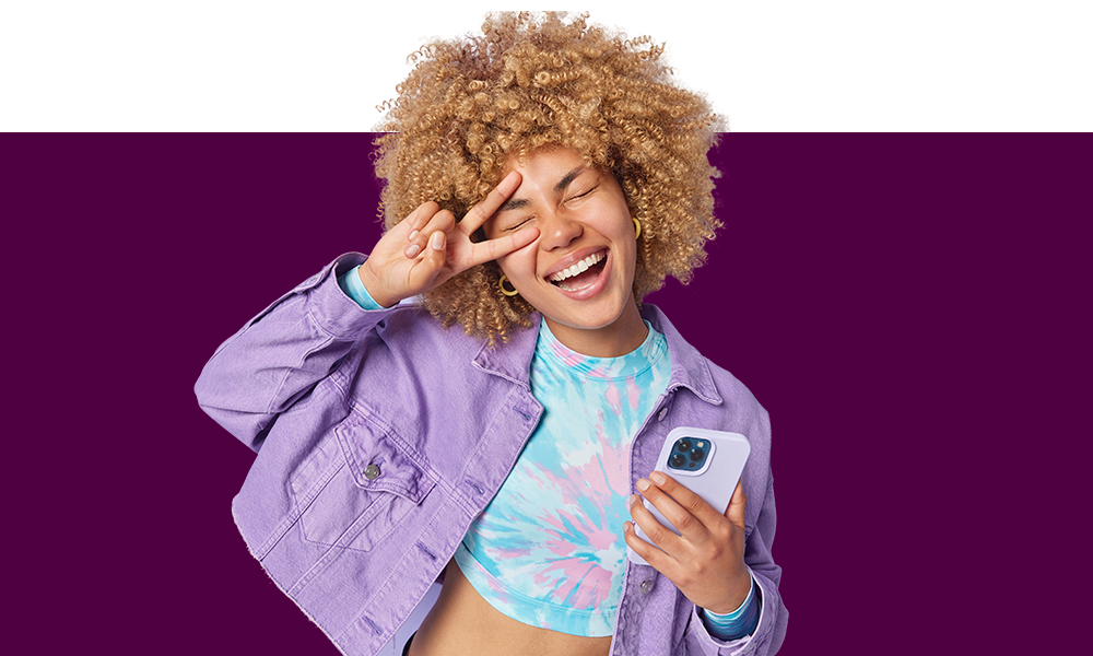Uma jovem sorridente segurando celular em fundo cor de açaí