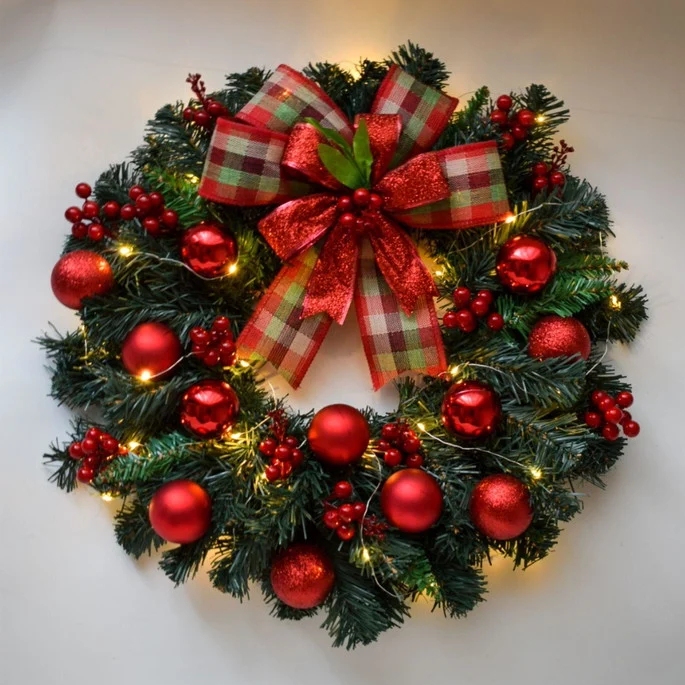 guirlanda de natal decorada com fitas, pinhas e ornamentos, pronta para dar boas-vindas ao espírito natalino em sua entrada.