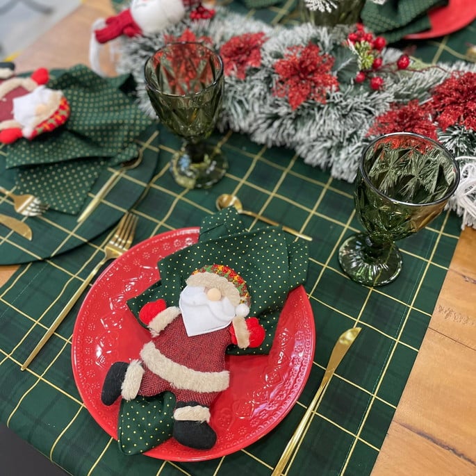 mesa posta decorada parNa o atal, com toalha festiva, talheres, pratos e enfeites natalinos, criando uma atmosfera calorosa para a ceia.