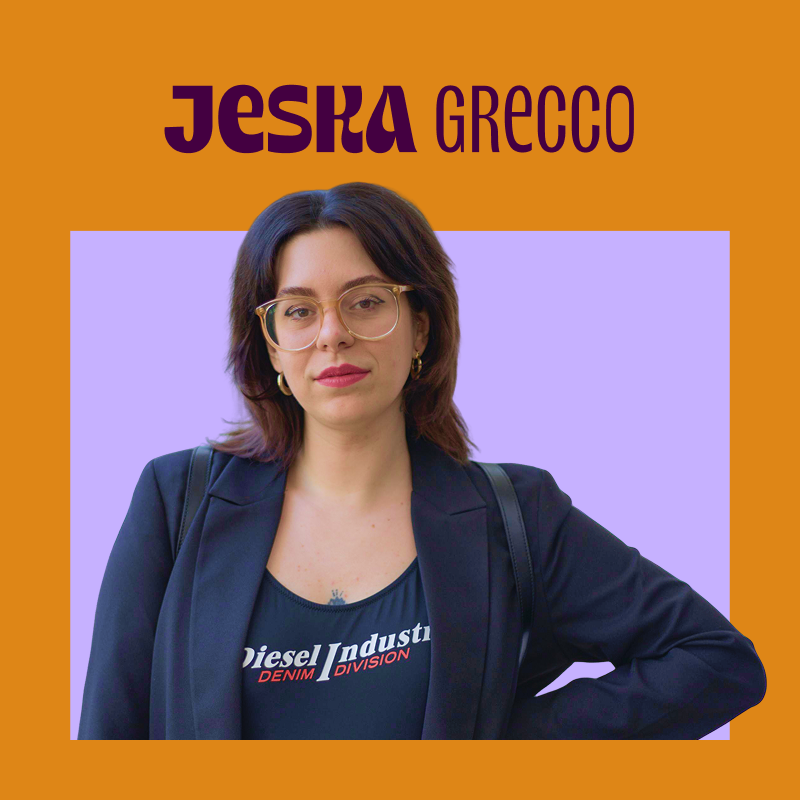 imagem traz foto da jeska grecco junto ao seu nome. jeska é veste óculos redondos grandes, um blazer azul sobre um body; ela tem pele clara e cabelos escuros na altura dos ombros.