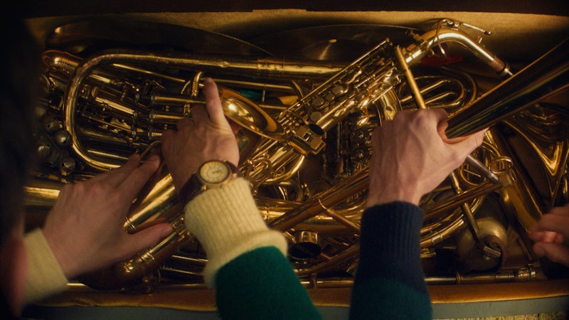 The Auburn Twins reach into a chest full of gold-colored, brass musical instruments.