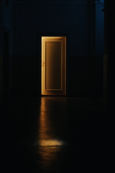 A door in a dark room is slightly ajar so that the golden light from the next room pours in—symbolising confidence in gold.