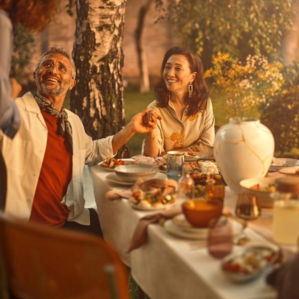 A successfully retired woman, partly due to gold's potential for protection, sits outside at a table surrounded by her family