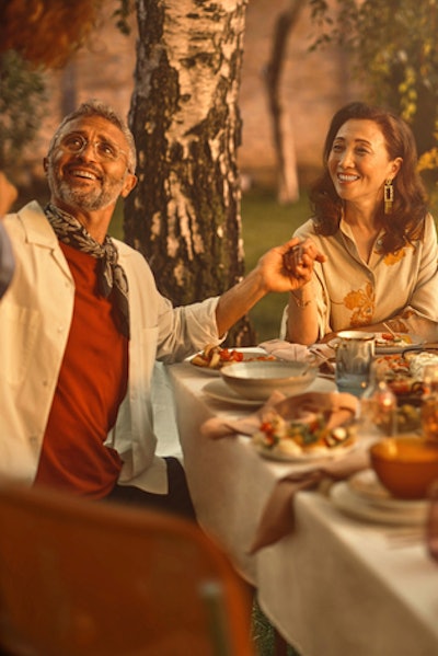 A retired woman, who has benefited from gold over the short and long term, sits outside at a table for a meal with her family