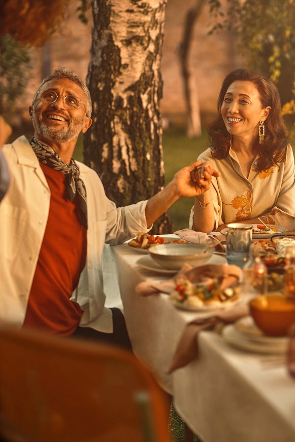 A successfully retired woman, partly due to gold's potential for protection, sits outside at a table surrounded by her family