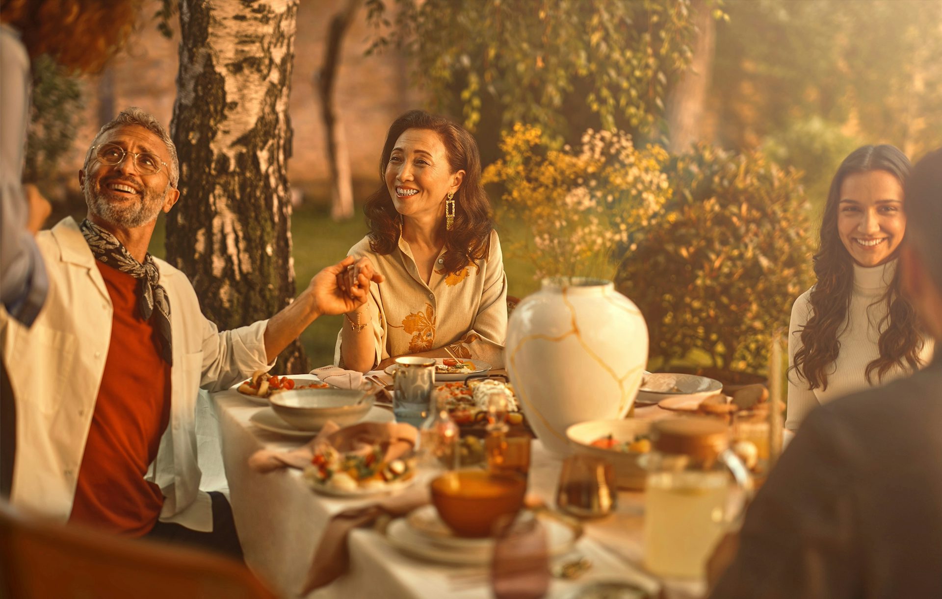 A retired woman, who has benefited from gold over the short and long term, sits outside at a table for a meal with her family