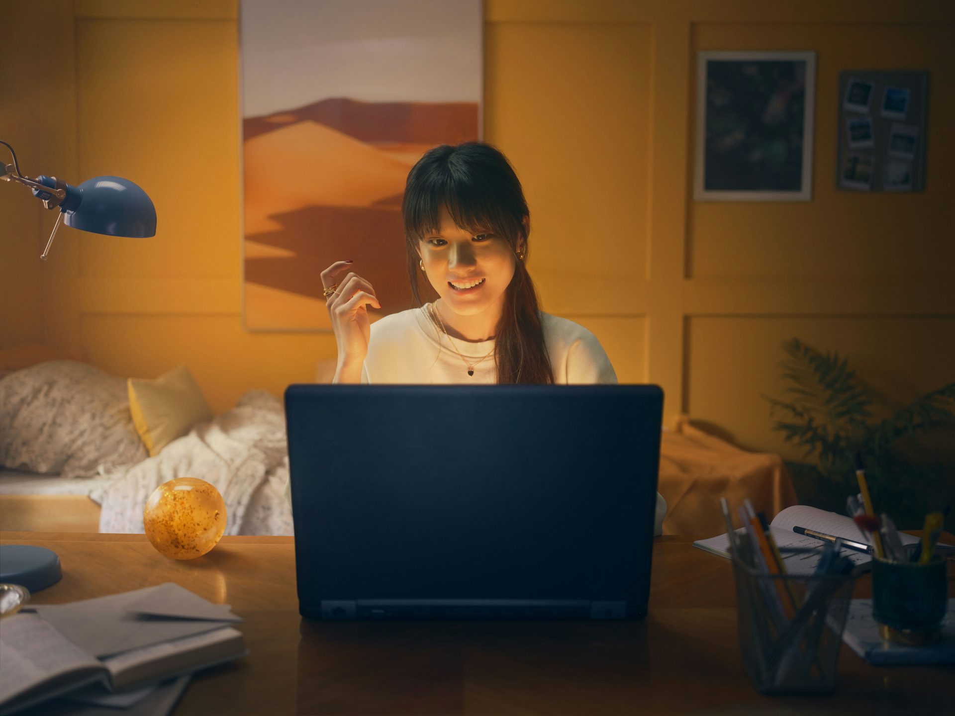 A young woman sits at her childhood bedroom desk in front of her laptop. She is learning how to buy gold for the first time.