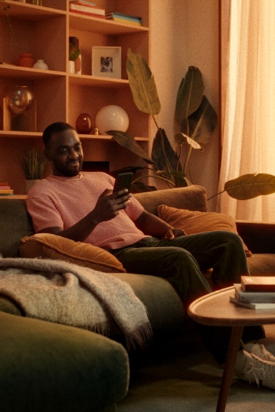 Man sitting on a couch with his phone looking pleased